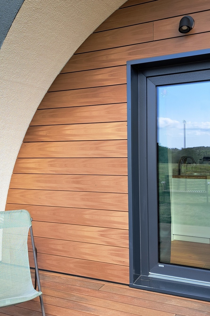 Facciata in legno composito Silvadec con rivestimento orizzontale installato su una casa contemporanea, che mette in risalto il contrasto tra il legno composito e le cornici delle finestre in alluminio antracite